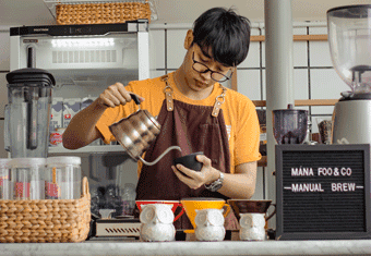 A teen barista prepares coffee.